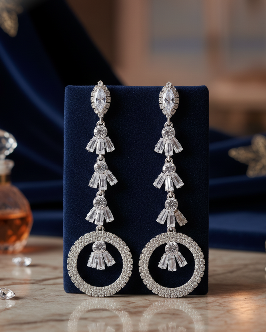Pair of silver earrings on a dark blue stand with a blurred background