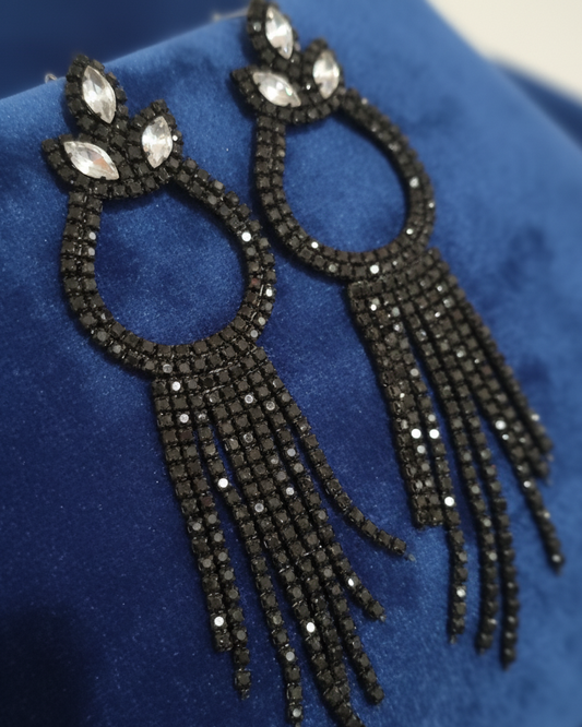 Black beaded earrings on a blue fabric background
