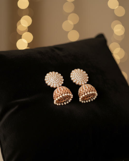 Pair of pearl earrings on a black pillow with blurred lights in the background