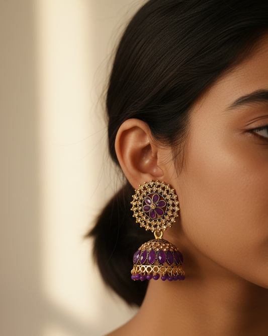 Close-up of a woman wearing a gold and purple earring with a blurred background