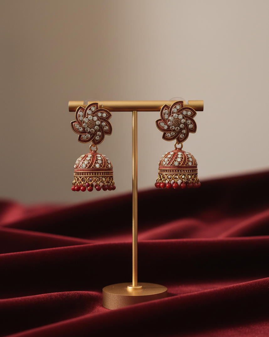 Decorative earrings on a gold stand with a red fabric background