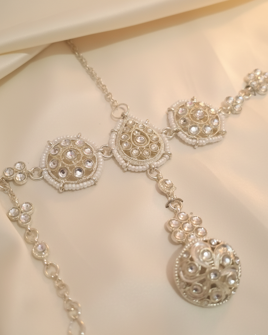 Delicate silver necklace with intricate designs on a soft beige background