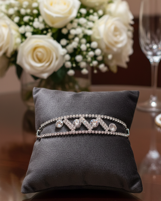 Diamante tiara on a black cushion with a bouquet of white roses in the background