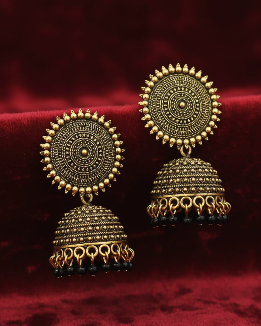 Pair of gold earrings on a red fabric background