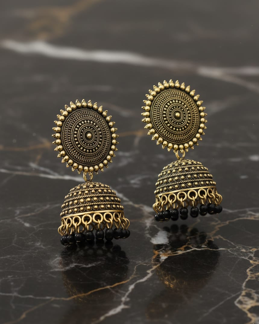 Pair of gold and black earrings on a marble surface